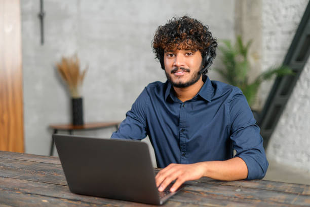 istock Friendly and optimistic curly middle eastern businessman in wireless headset device communicating with colleagues and customers online 1364994153