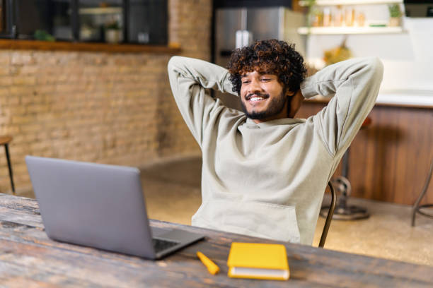 istock Male student resting with hands behind his head and looking at the laptop screen while watching lecture at home 1364994251