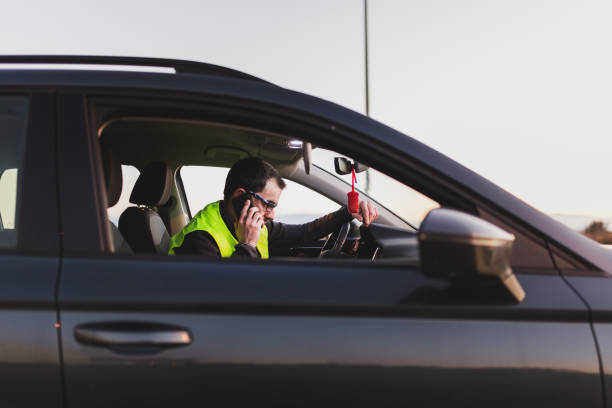 Man with car breakdown. Reflective vest and the hood raised calling the assistance tow truck.