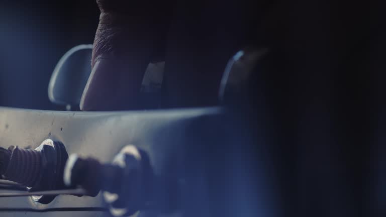 The musician tunes the guitar by turning the tuning pegs. Closeup of the left hand. Macro shooting. Depth of field