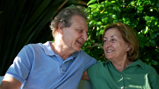istock Happy senior couple sitting outside at park bench 1364998636