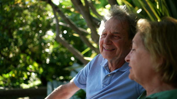 istock Happy senior couple sitting outside at park bench 1364998755