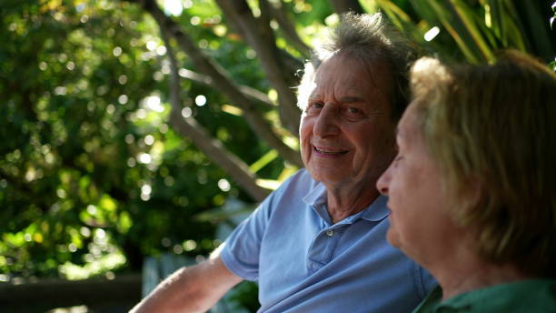 istock Happy senior couple sitting outside at park bench 1364998910