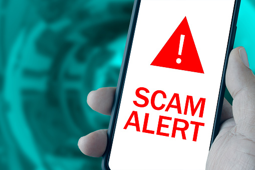 Scam Alert message on smartphone screen caused by cyber attack. Information security concept