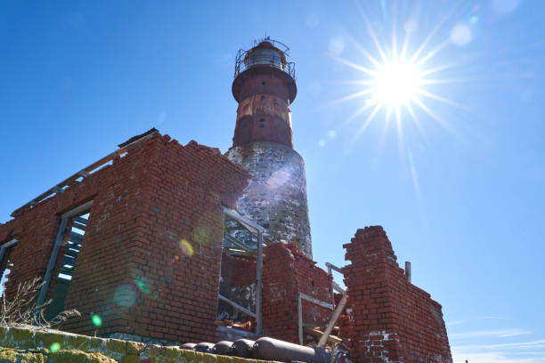 lighthouse built of red bricks, located on isla pinguino at the coast of patagonia in argentina, with sun flares reaching through the frame from top right corner to left bottom - corner stone wall brick imagens e fotografias de stock