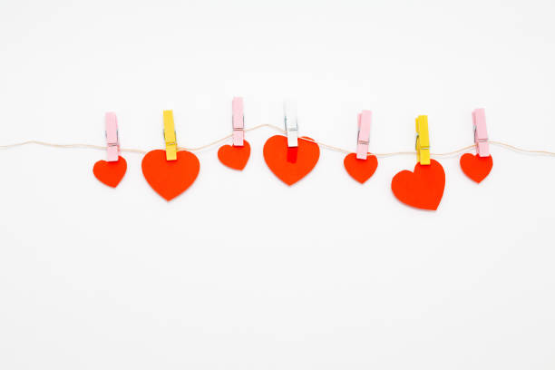 istock Red hearts with clothespins hanging on clothesline isolated on white background. 1365001367