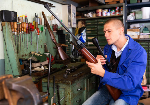 istock Gunsmith attaches a telescopic sight to rifle in weapons workshop 1365001979