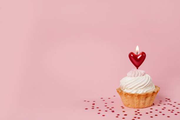 istock Valentine's day pink background. Vanilla cupcake decorated red heart candle 1365003027