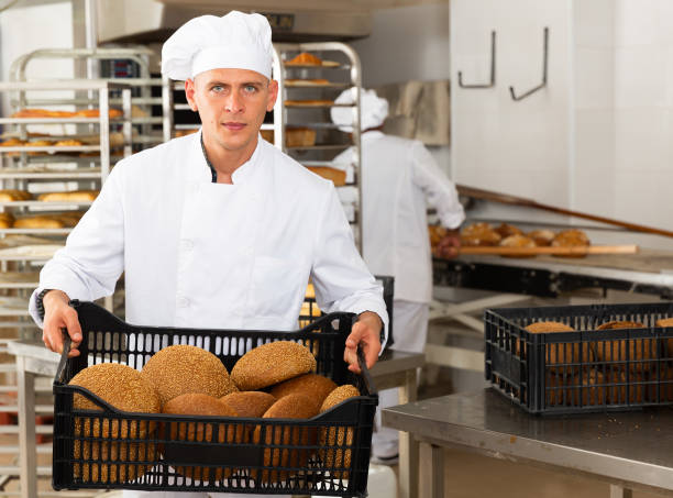 istock man in chefs uniform with bread in tray in bakery 1365003077