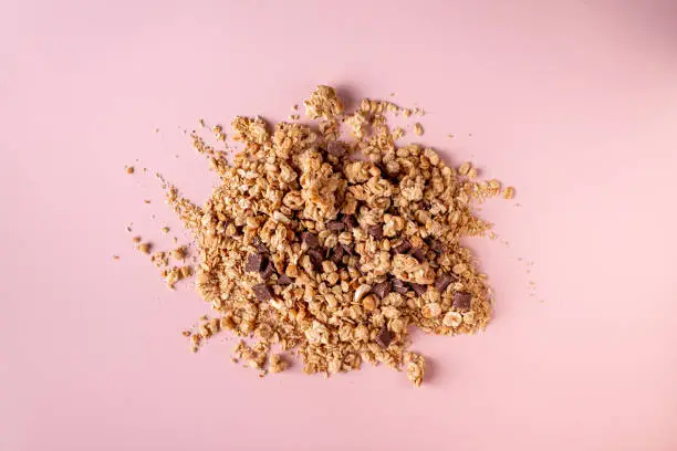 Photo of granola with nuts and chocolate on a beige background, flat lay