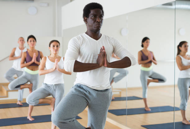 istock Focused aframerican standing in Eka Pada Pranamasana during group yoga training 1365004589