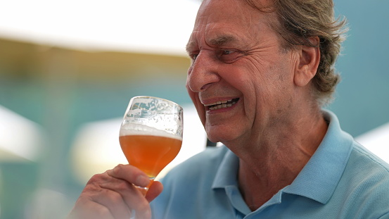 Happy senior man drinking beer with friends in conversation