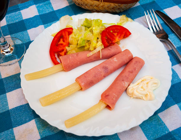 Appetizing dish of white asparagus rolls with ham, garlic sauce and vegetable salad
