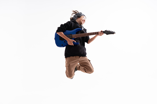 Handsome young boy playing an electric guitar and jumping on White Background