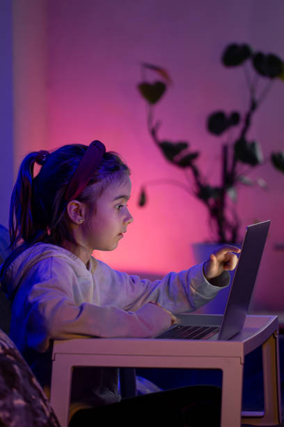 a little girl uses a laptop late at night. - child computer laptop little girls imagens e fotografias de stock