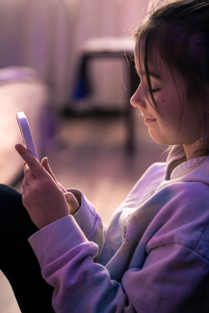 istock A little girl uses a smartphone while sitting in her room. 1365007302