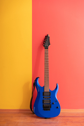 Blue Electric Guitar standing over colored wall