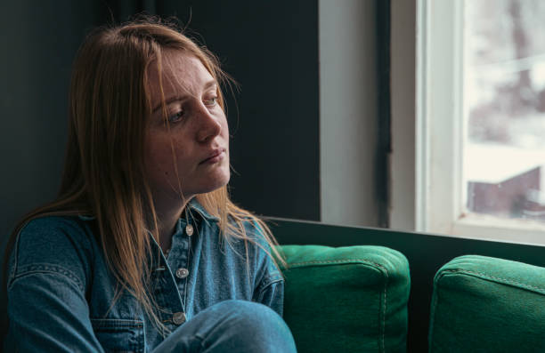 istock A cute young woman is sitting on the sofa by the window. 1365008890