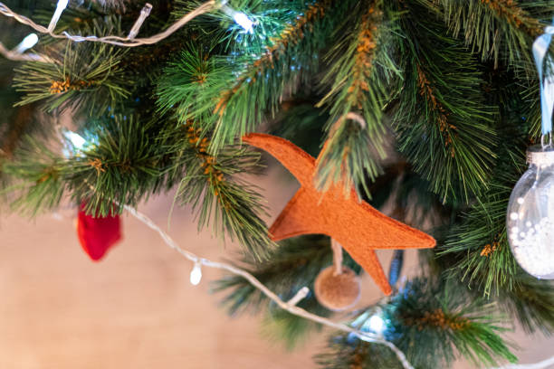 istock Orange star shape with many other ornaments on a green Christmas tree close up still 1365012889