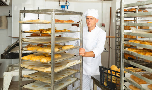 istock male baker rolling cart with bread in kitchen 1365013066
