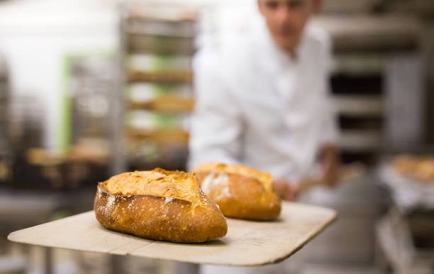 istock Baker takes out hot bread from oven 1365013122
