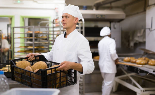 istock Male baker carrying crate with baked bread 1365013124