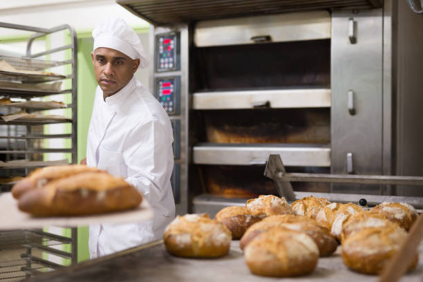 istock male baker with bread on baking shovel in kitchen 1365013130