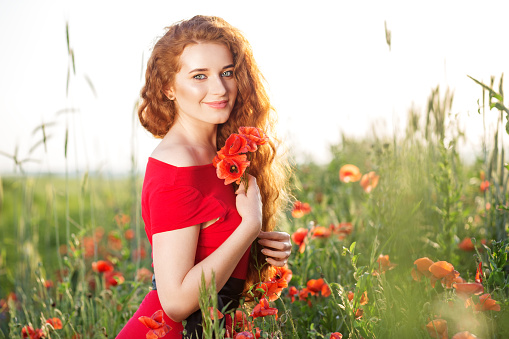 Pretty young woman smiles in poppy field. Beautiful make-up. The concept of health, nature, cosmetics and care.