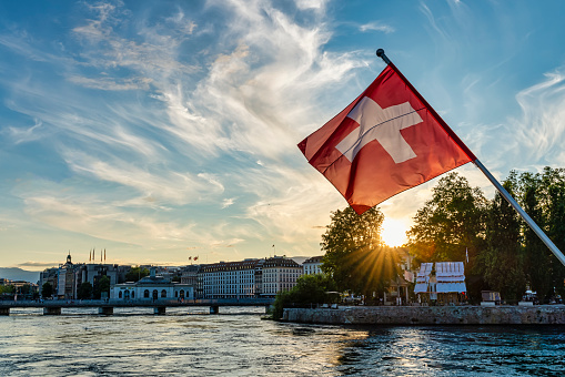 flag of switzerland in the foreground at sunset in Geneva city, Switzerland. lake Leman.