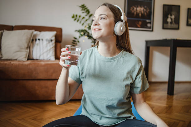 istock Young woman drinks water at home after home exercise 1365015578