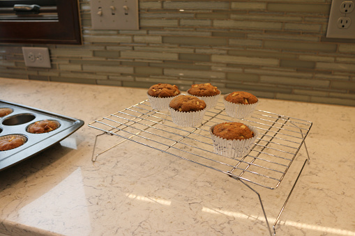 Baking homemade healthy whole wheat grain apple fruit muffins in a white modern gourmet luxury kitchen, with red accents and stainless steel high end appliances.