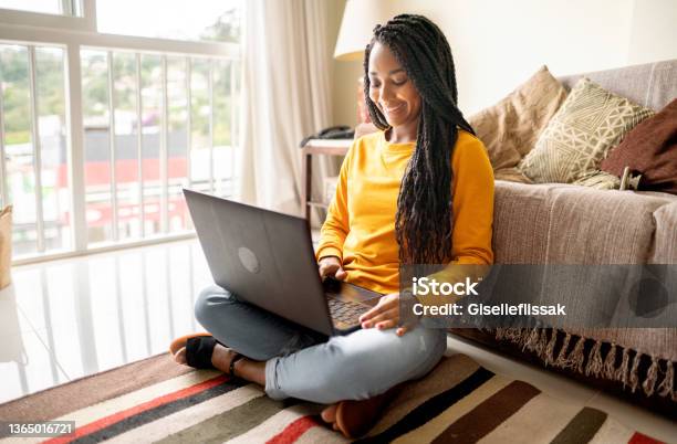 Smiling young woman using laptop on her living room floor