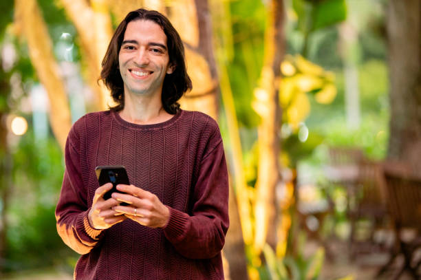 istock Young man smiling while standing outside and texting on his phone 1365017042