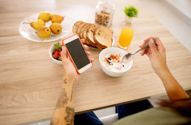 istock Woman checking her phone while eating a healthy breakfast 1365017929