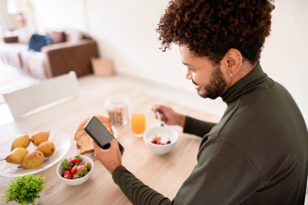 istock Young man checking his social feeds while eating a healthy breakfast 1365019379