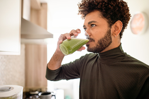 Young man drinking a healthy smoothie at home