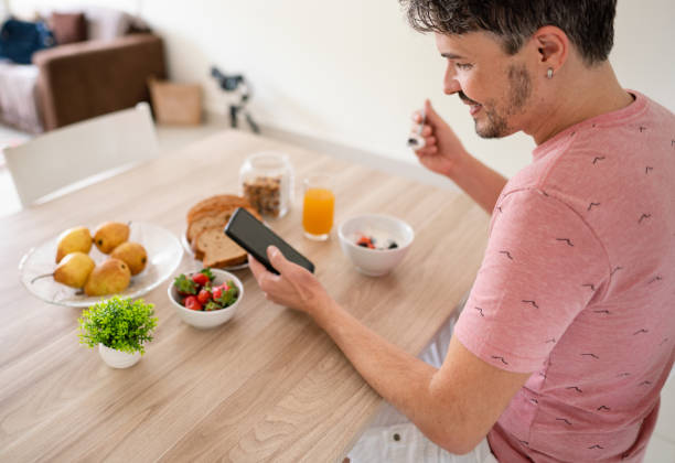 istock Man using his phone over a healthy breakfast in the morning 1365020112