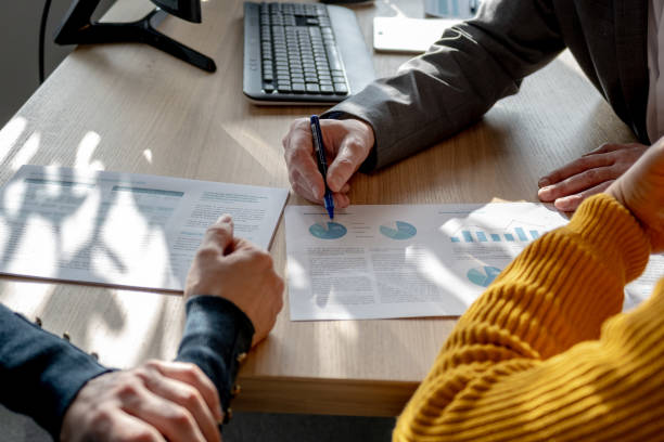 istock Close up of advisor's hand showing document to clients 1365021260