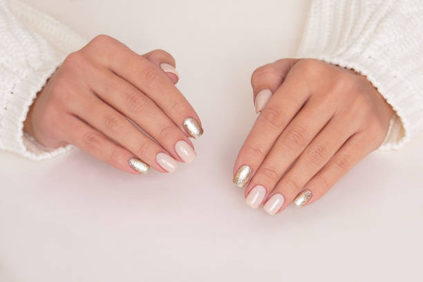 istock Female hands with beige and golden manicure nails 1365022821