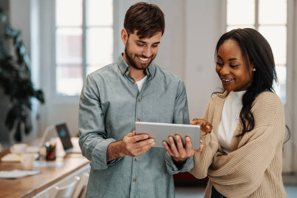 istock Smiling multi ethnic business team in office, using digital tablet 1365027661