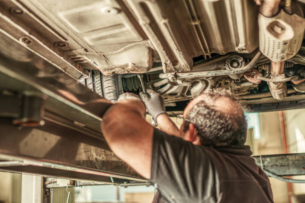istock Mechanic under a car lifted by a pneumatic jack fixing steering alignment in a garage 1365031695