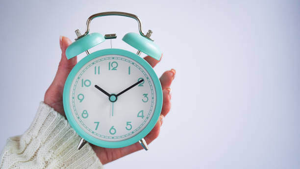 nahaufnahme der frau hand halten blauen retro-wecker weißen hintergrund, zeit auf der uhr ist zehn uhr zehn minuten, 10:10.zeit aufzuwachen, früher morgen. blue monday day konzept. speicherplatz kopieren. türkisfarbene uhr. - number alarm clock clock hand old fashioned stock-fotos und bilder