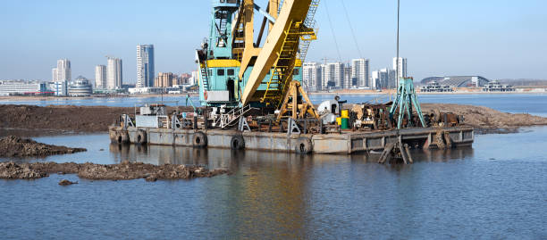 funktionierender baggerkran in küstennähe - industrial ship earth mover barge yellow stock-fotos und bilder