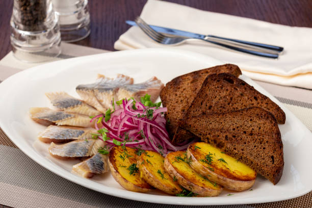 istock Herring with potatoes, red onion and black bread on white plate 1365039015