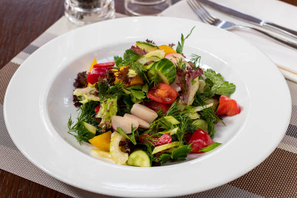 istock Green vegetable salad with tomatoes on white plate 1365039288