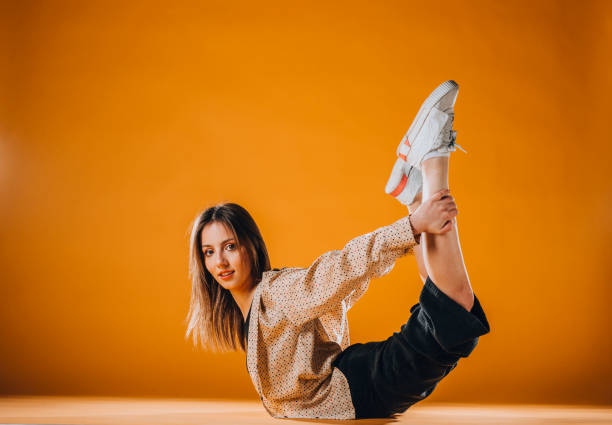 istock Young dancer doing acrobat moves isolated on orange wall 1365040334