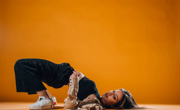 istock Young dance artist perform acrobat moves isolated on orange background 1365040342