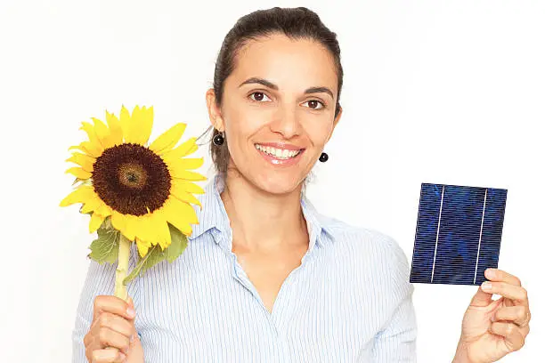 latin woman with a sunflower and a solar cell looking in the camera