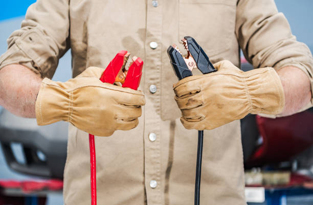 Car Mechanic with Jumper Cables in His Hands Car Mechanic with Energizer Jumper Cables For Car Battery. Heavy Duty Automotive Booster Cables for Jump Starting Dead or Weak Vehicle Battery. jumper cable stock pictures, royalty-free photos & images