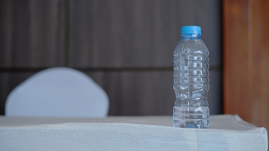 Bottle of mineral water with half remaining, blurred background